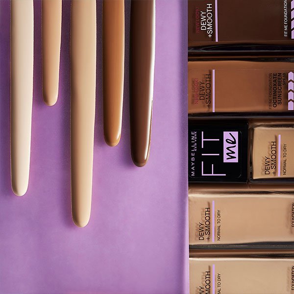 Foundation dripping down on purple background on the left and Maybelline Fit Me Dewy + Smooth foundations on the right