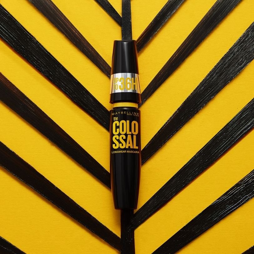 Close up of Maybelline The Colossal Longwear Mascara in front of yellow and black background
